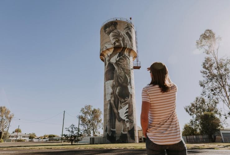 Woman admiring a painted water tower in Cunnamulla, QLD © Tourism and Events Queensland