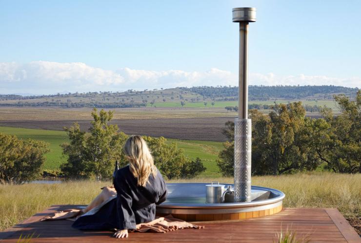 A person sitting beside an outdoor tub overlooking countryside, Gilay Estate, Quirindi, New South Wales © Gilay Estate