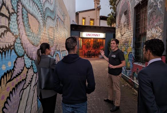 A group of people raising cocktails and glasses of beer around a wooden table in a dimly lit venue. with Local Sauce Tours, Sydney, New South Wales © Local Sauce Tours