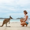 Woman admires a kangaroo on a white sand beach at Lucky Bay, Esperance, Western Australia © Tourism Australia