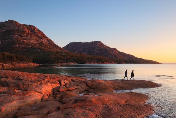 Couple walking on rock, Honeymoon Bay, Freycinet, Tasmania © Tourism Australia