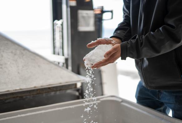 A man lets a hand full of sea salt cascade down at Tasman Sea Salt, East Coast, Tasmania © Tourism Australia