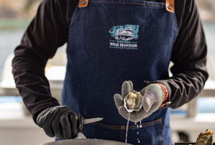 A man holding a shucked oyster, Tasmanian Wild Seafood Adventures, Hobart, Tasmania © Dearna Bond