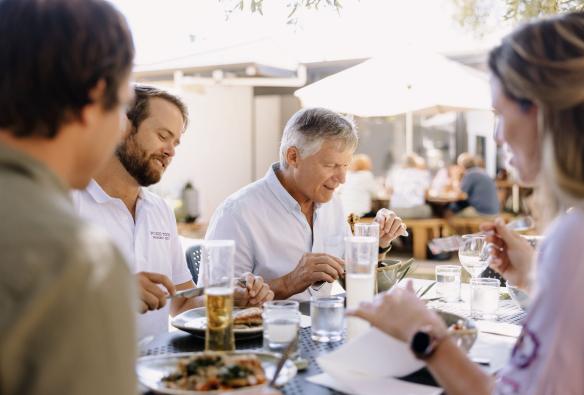 Diners sit around a table, enjoying a lunch in a leafy outdoor patio at Olio Bello, Australia’s South West, Western Australia © Tourism Australia