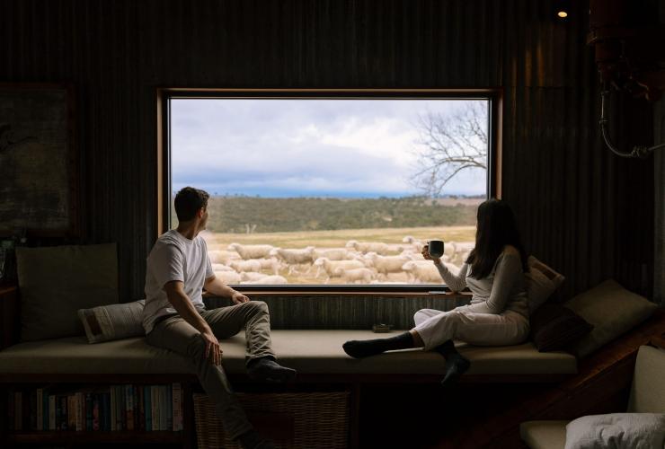 Couple watching sheep through a window at Wilga Station, Bathurst, New South Wales © Tourism Australia
