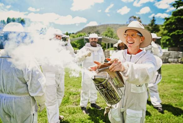 Man smiling as he uses a smoker at Bowral Honey Farm, Southern Highlands, New South Wales © Tourism Australia