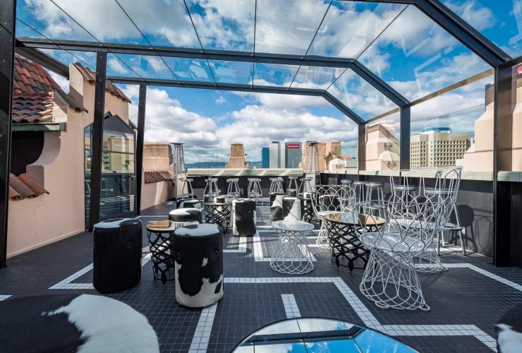 A stylish rooftop bar with a glass awning overlooking city buildings at Hennessy Bar, Adelaide, South Australia © Tourism Australia