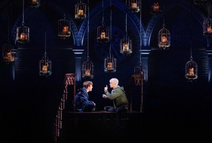 Two actors performing on stage beneath a set adorned with owls in cages at The Australian Company of Harry Potter and the Cursed Child, Victoria © The Australian company of Harry Potter and the Cursed Child.