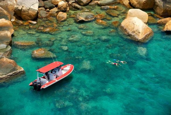 Aerial of a man and woman snorkelling among the fringing reef of Orpheus Island with a boat nearby at Orpheus Island Lodge, Queensland © Orpheus Island Lodge