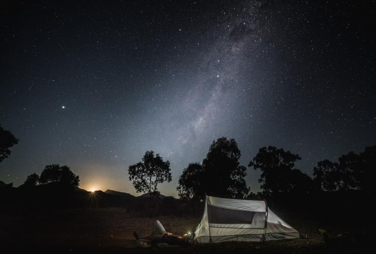 Man laying outside his tent looking up at the night sky in Warrumbungle National Park, New South Wales © Rob Mulally