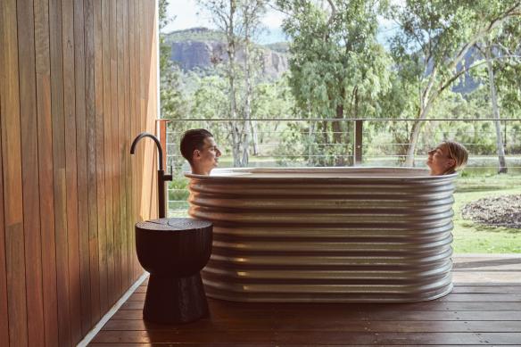 A couple relaxing in a bath on a balcony overlooking bushland, Mt Mulligan Lodge, Outback Queensland © Jason Ierace
