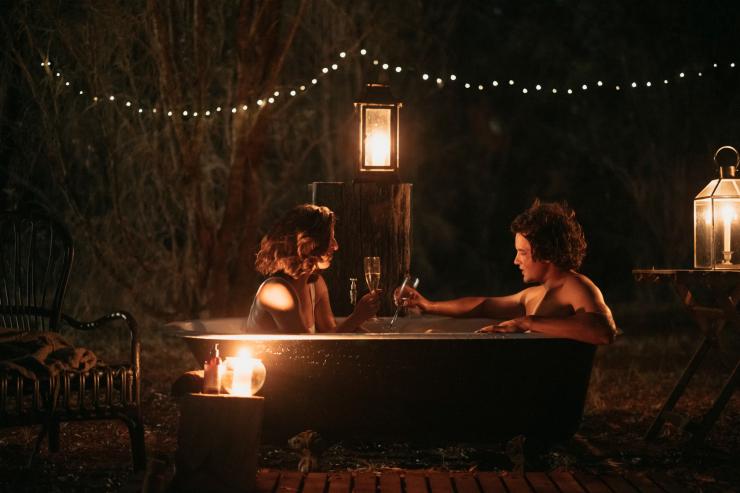 Two people sipping wine in an outdoor tub beneath lantern lights at night, Walk Talk Taste, Margaret River, Western Australia © Jarrad Seng