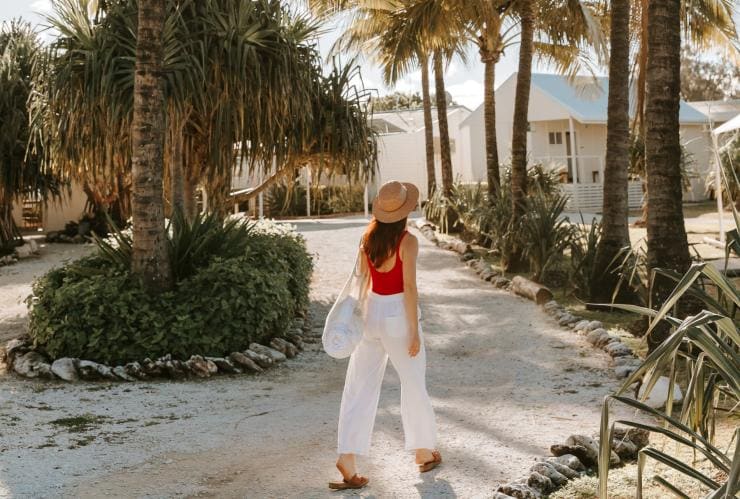 Woman walking beneath palm trees at Lady Elliot Island Eco Resort, Great Barrier Reef, QLD © Tourism and Events Queensland