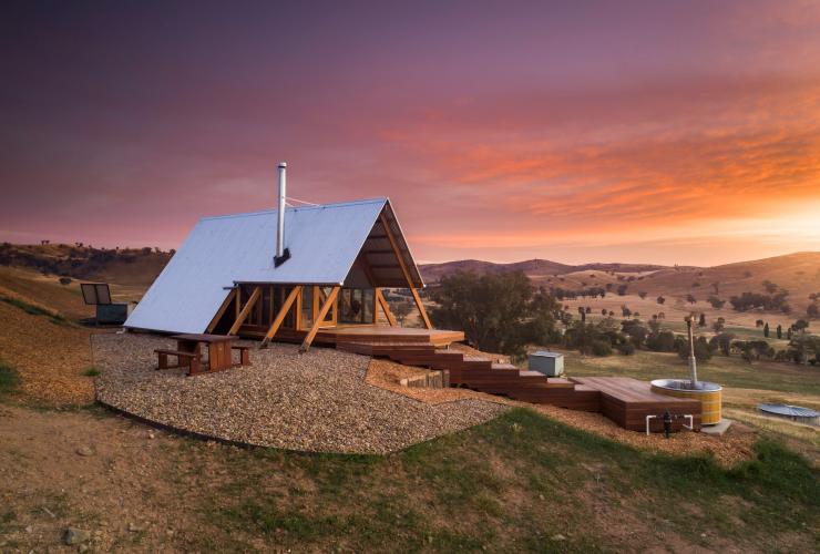 A tiny home with an outdoor tub among green hills during a vibrant sunset, Kimo Estate, Gundagai, New South Wales © Kimo Estate/Matt Beaver Photography