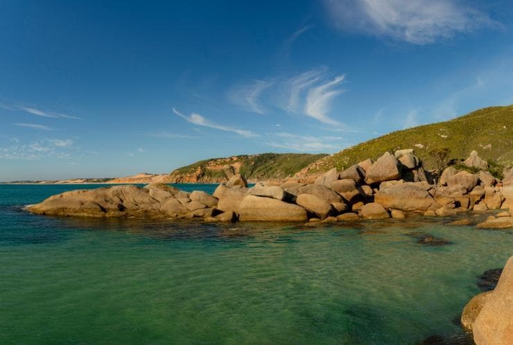 Clear blue water surrounded by smooth, sandstone boulders and grassy hills at Fairy Cove, Wilsons Promontory National Park, Victoria © Mark Watson, Visit Victoria