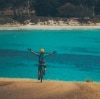 A person on a mountain bike with their arms in the air overlooking clear blue ocean in Maria Island National Park, Tasmania © Matt Staggs