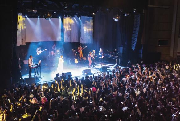 A band performing onstage in front of a large crowd with their hands in the air during Vivid Sydney, Sydney, New South Wales © Destination NSW