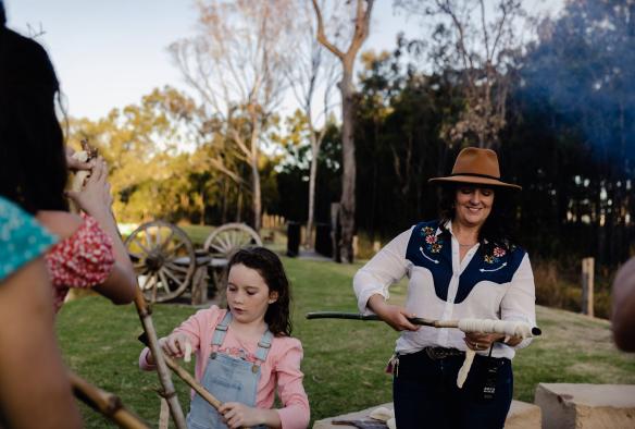 Family ready to roast dough over the fire at Splitters Farm, Sharon, Queensland © Tourism Australia