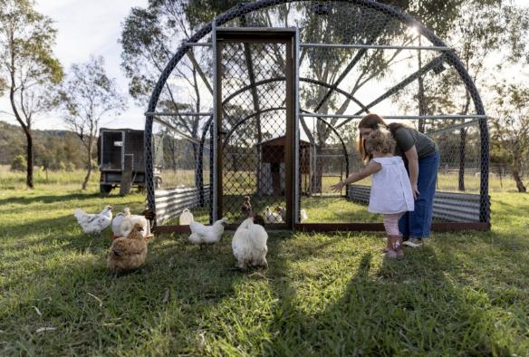 Child and mother with chickens at Starline Alpaca Farm, Broke, New South Wales © Tourism Australia
