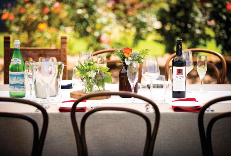 A tablescape of wine and flowers in a garden, Pizzini Wines, King Valley, Victoria © Pizzini Wines