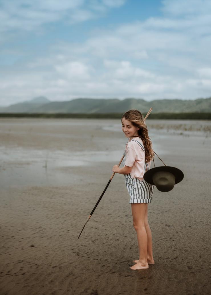 A child standing on mudflats holding a spear with Walkabout Cultural Adventures, Cooya Beach, Queensland © Tourism and Events Queensland