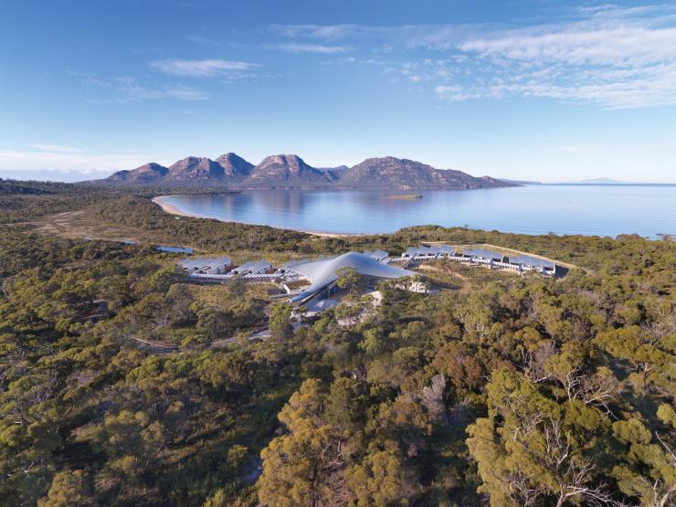 Aerial view over a luxurious lodge surrounded by bushland with a calm bay and mountains in the distance, Saffire Freycinet, Freycinet, Tasmania © Saffire Freycinet