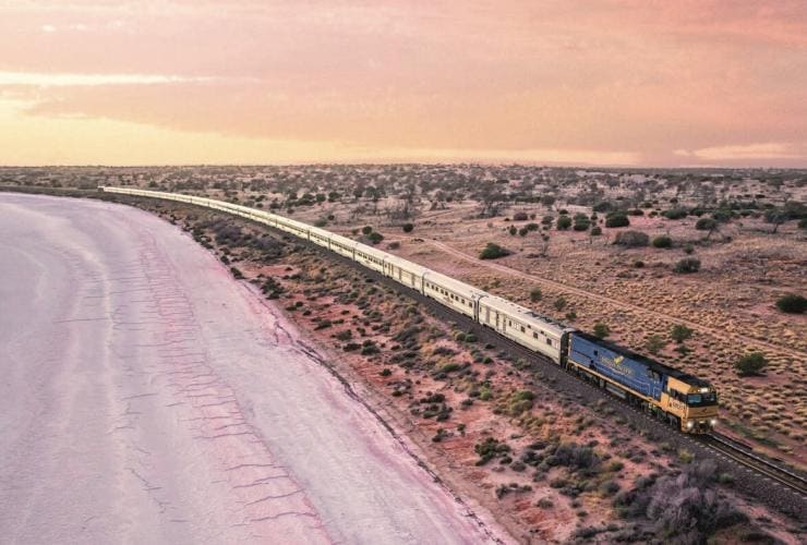 A train driving past a pink lake, Indian Pacific Train, Lake Hart, South Australia © Tourism Australia