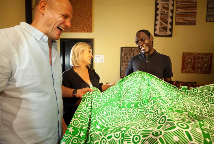 Deux personnes debout avec un artiste aborigène admirant un tissu sérigraphié, Tiwi by Design, Tiwi Islands, Territoire du Nord © Tourism Australia