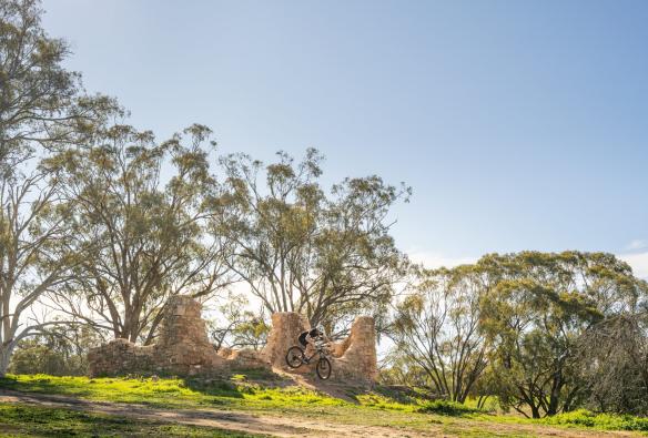 Une personne sur un VTT volant dans les airs au-dessus d'une pile de briques à Melrose, Flinders Ranges et arrière-pays, Australie du Sud © Heidi Who Photos