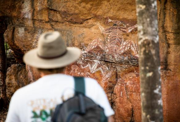 Un visiteur admirant un mur recouvert d'art rupestre ancien au Kakadu National Park, Territoire du Nord © Tourism NT