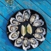 Vue de dessus d'une assiette d'huîtres disposées en cercle avec des quarts de citrons au centre, sur une table bleue du Get Shucked, Bruny Island, Tasmanie © Adam Gibson/Tourism Tasmania