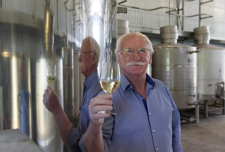 Ken Helm, directeur et vigneron de Helm Wines, un verre de vin blanc à la main à côté de tonneaux en métal, Canberra Wine District, Nouvelle-Galles du Sud © Irene Dowdy