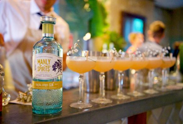Une bouteille de gin « Coastal Citrus » posée sur le comptoir d'un bar, à côté d'une rangée de cocktails fraîchement préparés au Manly Spirits Co., Manly, Nouvelle-Galles du Sud © Martin Vivian Pearse
