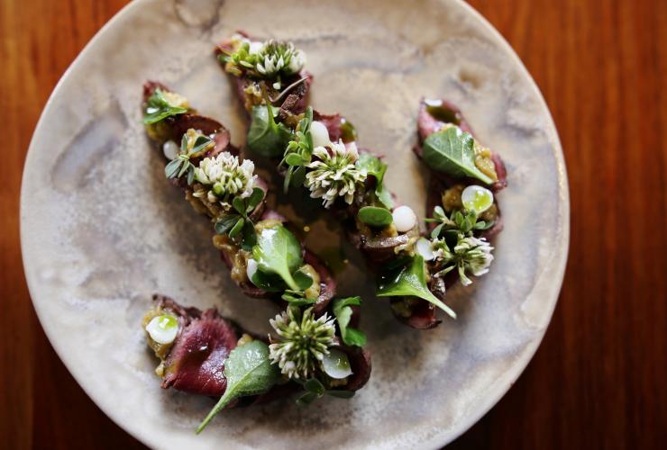Vue aérienne d'une assiette gastronomique de kangourou grillé, gubinge, herbes et ail sauvage, Orana, Adélaïde, Australie du Sud © Orana