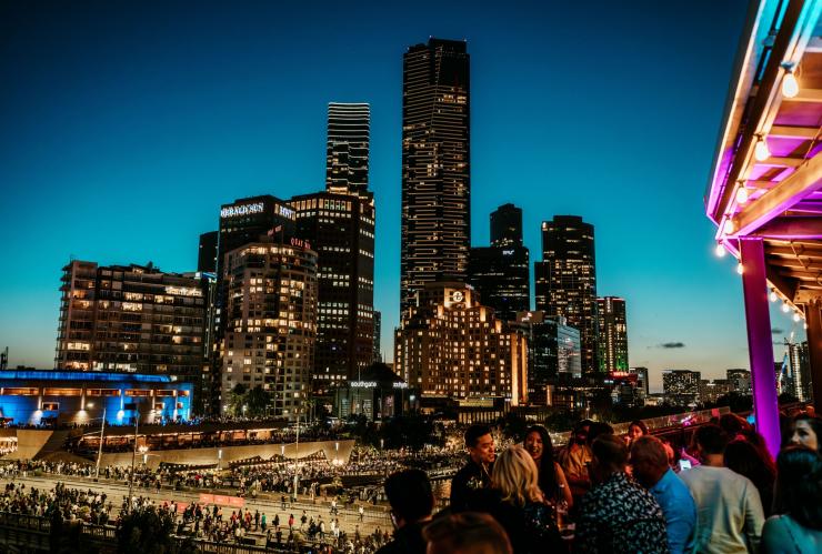 Un groupe de personnes sur un rooftop avec le paysage urbain de Melbourne en arrière-plan au Transit Rooftop Bar, Melbourne, Victoria © Michael Lack / Visit Victoria