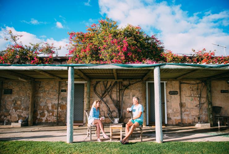 Deux personnes dégustant un café sur le balcon d’un lodge recouvert de buissons fleuris, Dirk Hartog Island Eco Lodge, Shark Bay World Heritage Area, Australie Occidentale © Tourism Western Australia