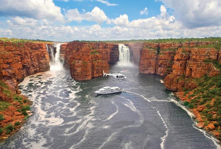 Un hélicoptère survolant un bateau de croisière à côté de deux grandes cascades, True North Cruise, The Kimberley, Australie Occidentale © North Star Cruises Australia