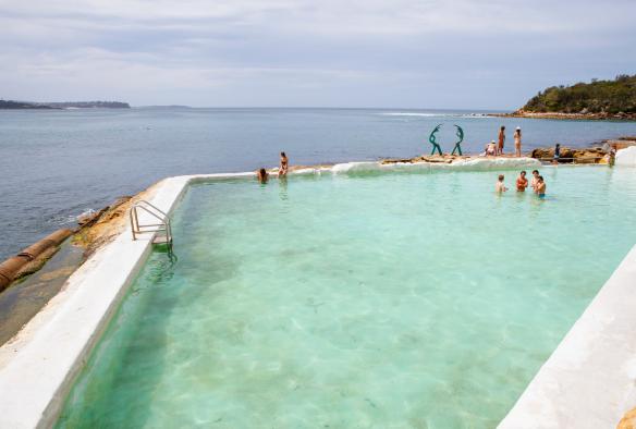 Des personnes nageant dans les eaux bleues limpides de la Fairy Bower Ocean Pool, avec l'océan en arrière-plan à Manly, Nouvelle-Galles du Sud © Destination NSW