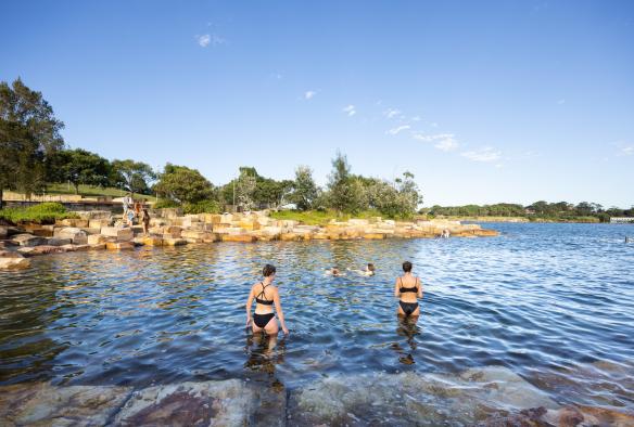 Des personnes debout et nageant dans les eaux protégées de Marrinawi Cove lors du coucher du soleil à la Barangaroo Reserve, Sydney, Nouvelle-Galles du Sud © Images for Business