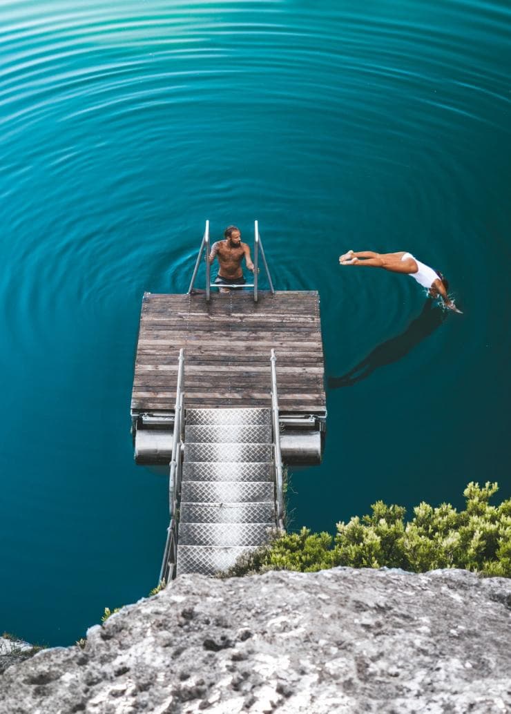 Femme plongeant d'une plateforme dans le Little Blue Lake, Limestone Coast, Australie du Sud © As We Wander