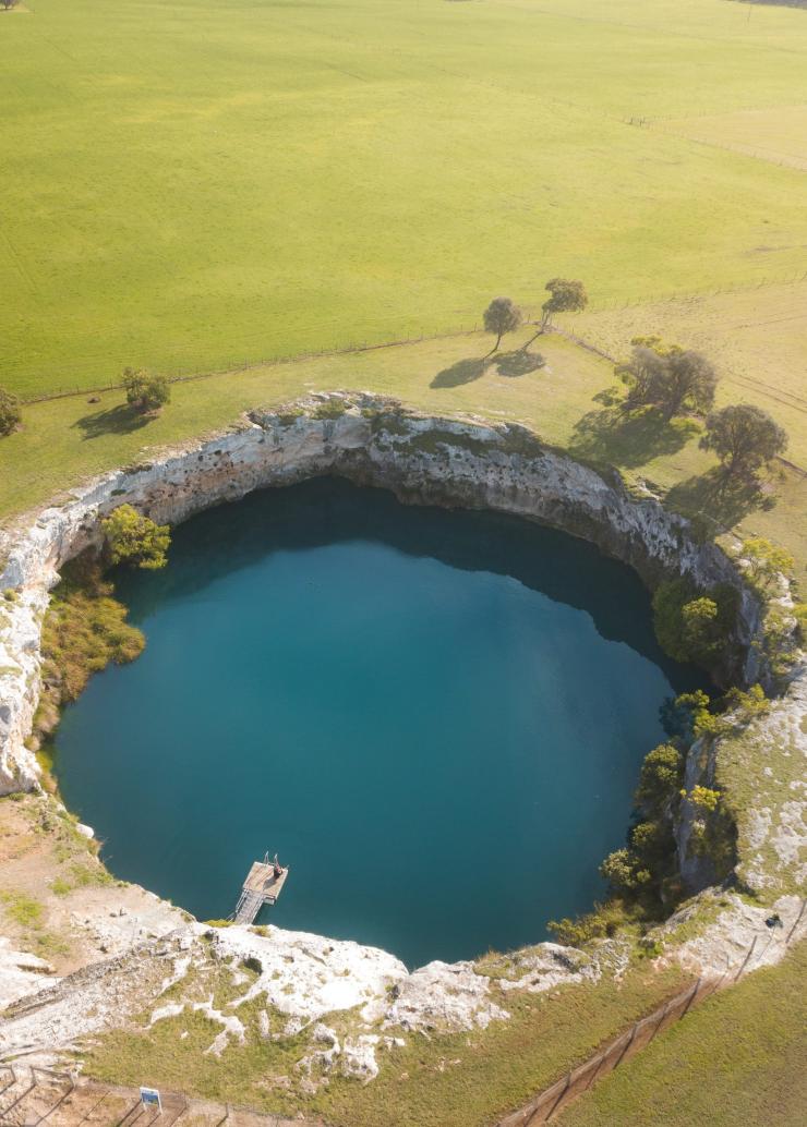 Vue aérienne d'un lac dans un cratère entouré de pâturages verts à Little Blue Lake, Mount Gambier, Australie du Sud © @Mitch.Toft