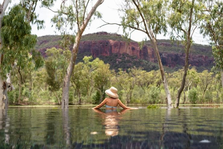 Une femme se baignant dans une piscine reflétant les arbres et les montagnes des environs du Mt Mulligan Lodge, Mount Mulligan, Queensland © The Rambler Co 