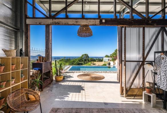 Une grande pièce ouverte remplie de plantes menant à une piscine offrant des vues imprenables sur la verdure et l'océan à Blackbird, Byron Bay, Nouvelle-Galles du Sud © Destination NSW