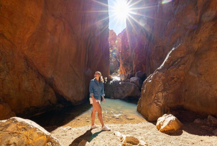 Une femme marchant le long des imposantes parois rocheuses rouges de Standley Chasm, West MacDonnell Ranges National Park, Territoire du Nord © Tourism NT/Charlie Bliss