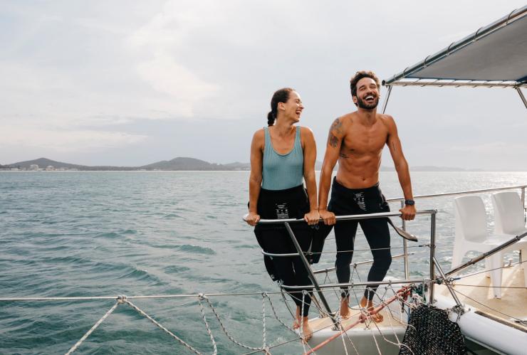 Un couple souriant se tenant debout à bord d’un bateau, Dolphin Swim Australia, Port Stephens, Nouvelle-Galles du Sud © Destination NSW