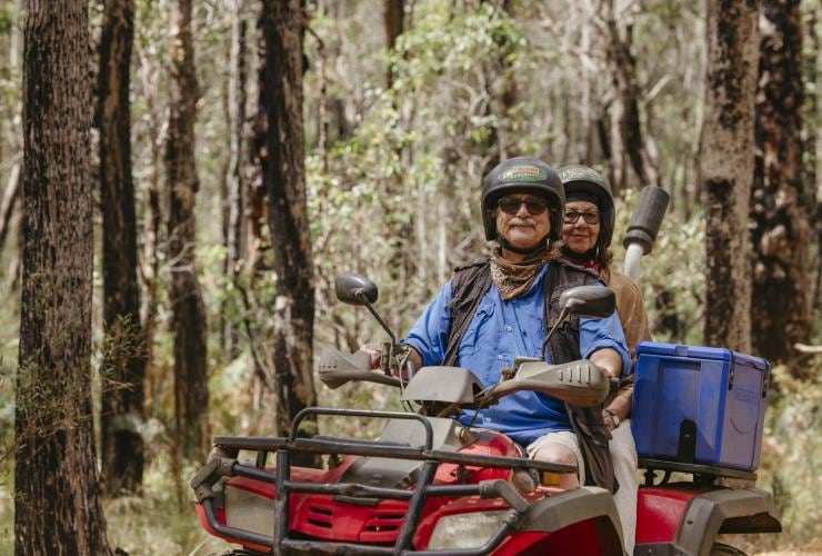 Pasangan lanjut usia mengendarai motor ATV melintasi semak-semak bersama Eco Adventures Margaret River, Western Australia © Tourism Australia