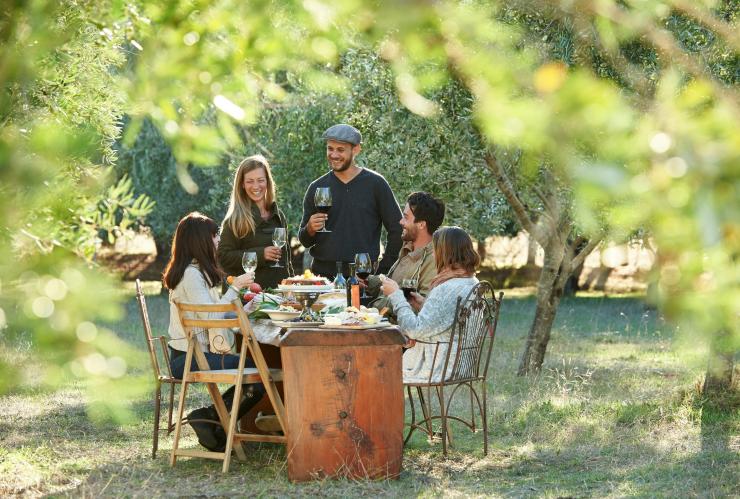 Beberapa teman berkumpul di sekitar meja makan di tempat terbuka sambil menikmati segelas anggur di Olio Bello, Margaret River, Western Australia © Tourism Western Australia