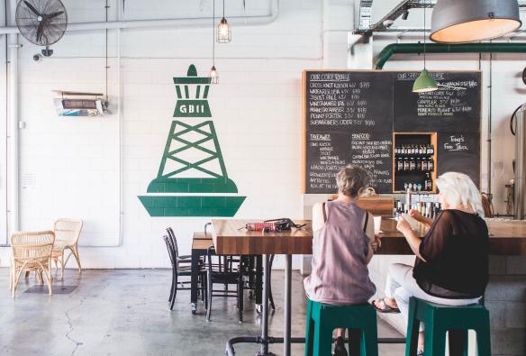Dua orang duduk bersama di kursi bar berwarna hijau di tempat bernuansa rustik dan industrial, Green Beacon Brewing Co., Fortitude Valley, Queensland © Anwyn Howarth