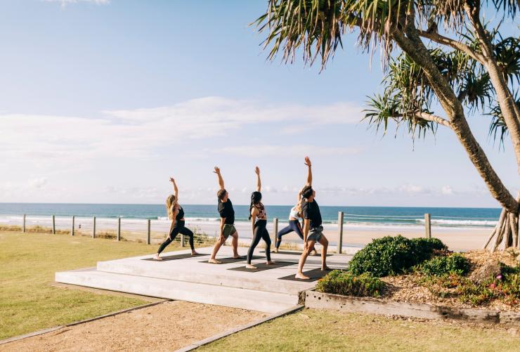 Tamu-tamu menikmati sesi yoga pagi di tepi pantai, Elements of Byron, Byron Bay, NSW © Destination NSW