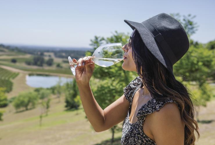 Seseorang menyesap white wine di kebun anggur, Bistro Molines, Hunter Valley, New South Wales © Destination NSW